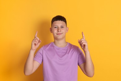 Photo of Teenage boy pointing at something on orange background