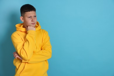 Photo of Portrait of teenage boy on light blue background, space for text