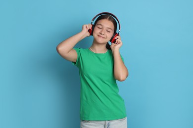 Photo of Teenage girl in headphones on light blue background