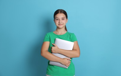 Photo of Teenage girl with laptop on light blue background