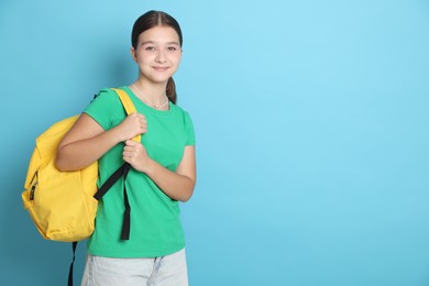 Photo of Teenage girl with backpack on light blue background, space for text