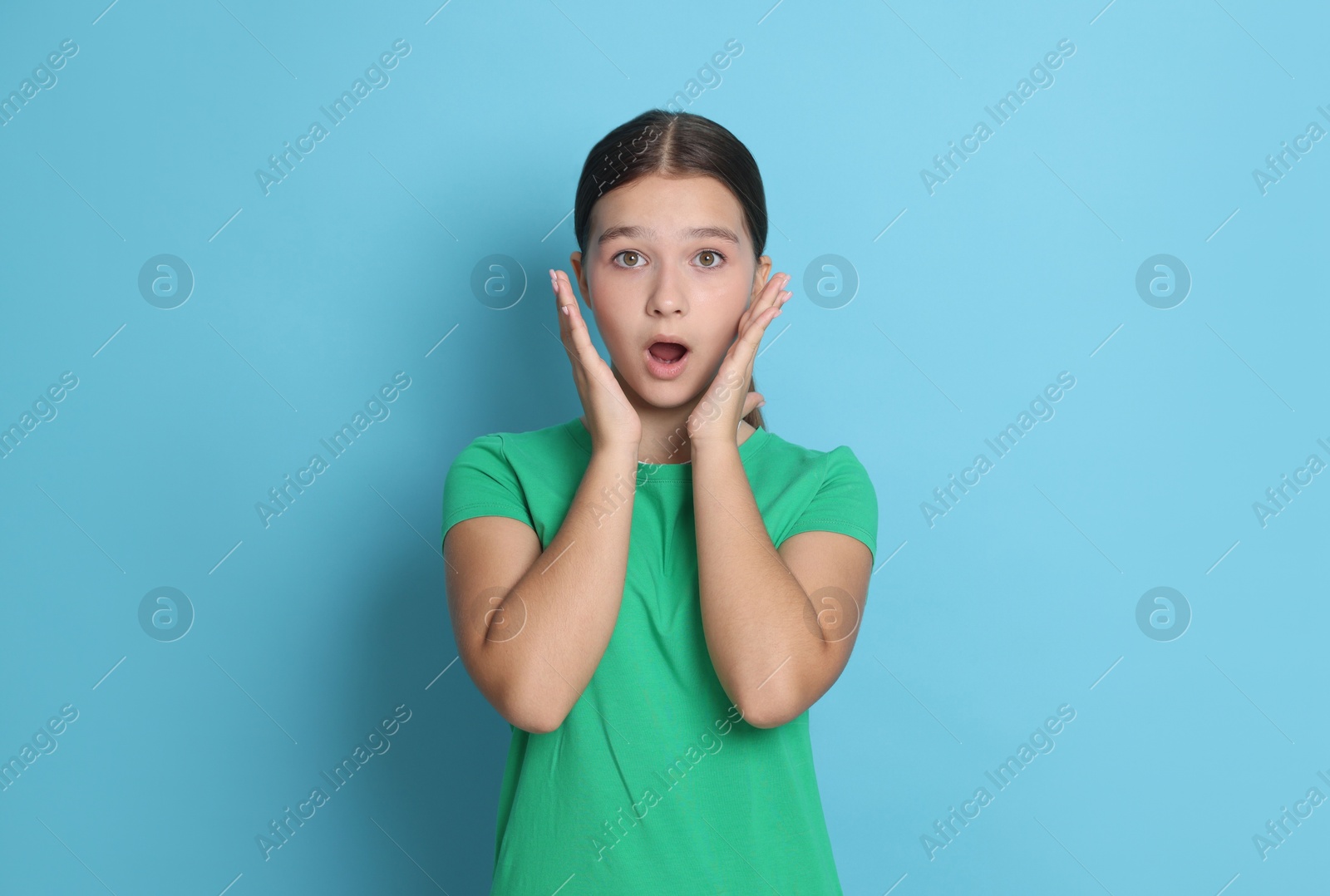Portrait of shocked teenage girl on light blue background Photo of Portrait of shocked teenage girl on light blue background
