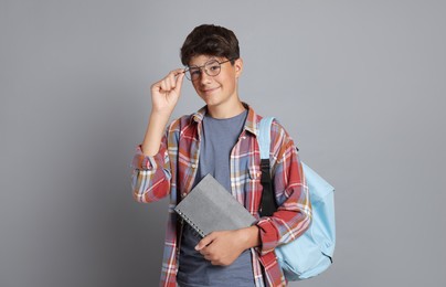 Photo of Teenage boy with notebook and backpack on grey background