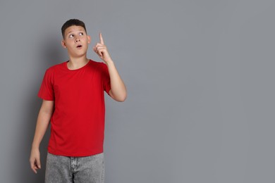 Photo of Teenage boy pointing at something on grey background