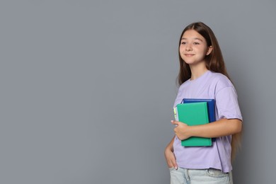 Photo of Teenage girl with books on grey background, space for text