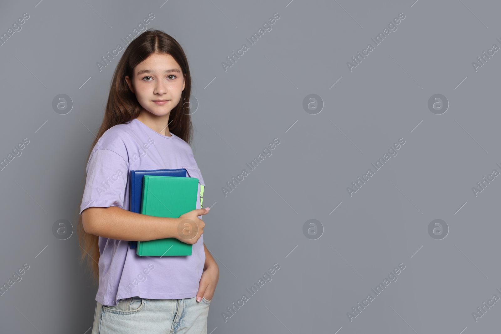 Teenage girl with books on grey background, space for text Photo of Teenage girl with books on grey background, space for text