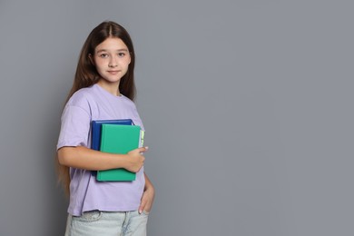 Photo of Teenage girl with books on grey background, space for text