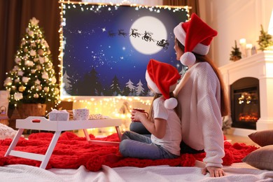 Image of Mother and daughter watching Christmas movie using video projector at home