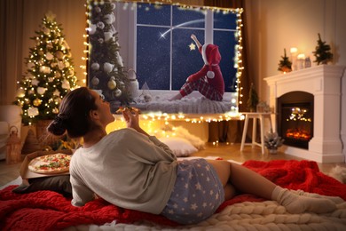 Image of Woman eating pizza and watching Christmas movie using video projector at home