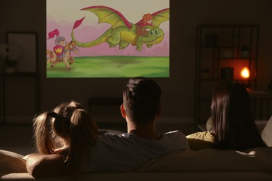 Image of Family watching cartoon using video projector on sofa in evening