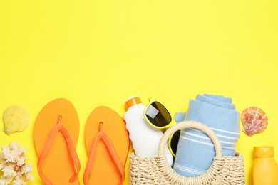 Photo of Flat lay composition with beach towel and other summer accessories on yellow background. Space for text