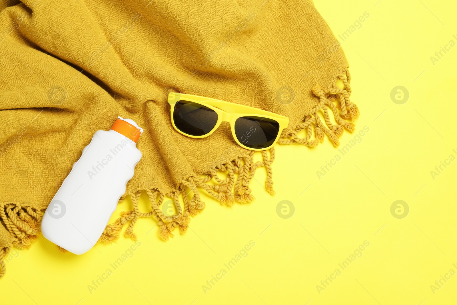 Beach towel, sunglasses and sunscreen on yellow background, flat lay. Space for text Photo of Beach towel, sunglasses and sunscreen on yellow background, flat lay. Space for text