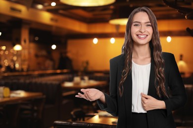 Image of Young hostess in uniform welcoming to restaurant