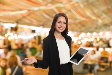 Image of Young hostess with tablet computer welcoming to restaurant