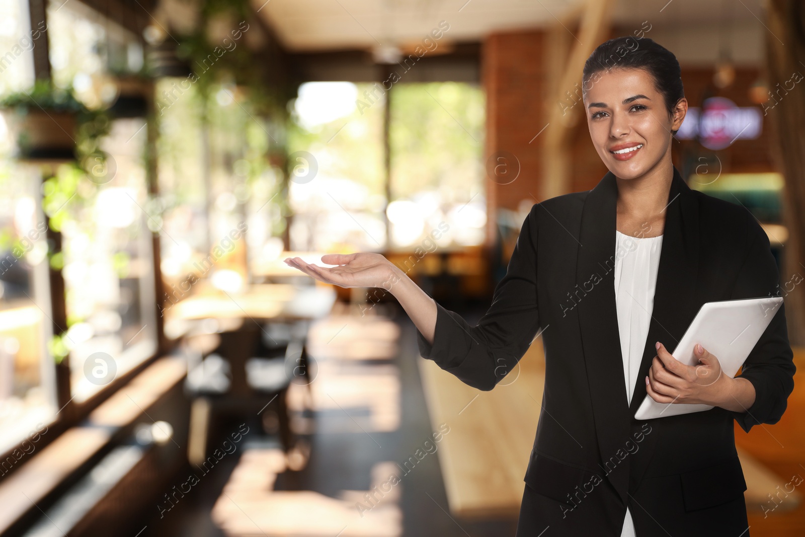 Image of Young hostess with tablet computer welcoming to restaurant
