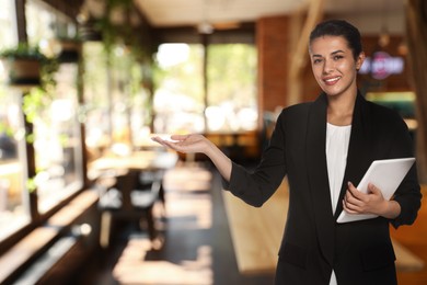 Image of Young hostess with tablet computer welcoming to restaurant