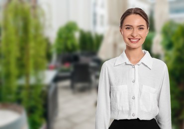 Image of Young smiling hostess in uniform at outdoor restaurant