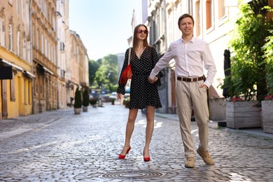Photo of Lovely couple walking together on city street, space for text