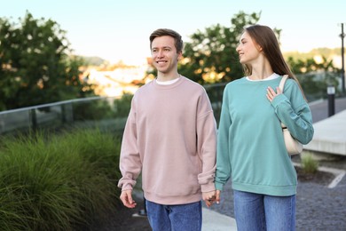 Photo of Lovely couple walking together on city street, space for text