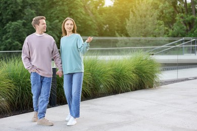 Photo of Lovely couple walking together on city street, space for text