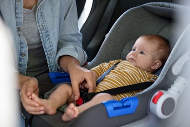 Photo of Mother fastening her baby in car seat, closeup