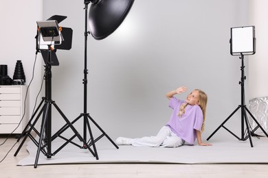 Photo of Little girl on light grey background in photo studio with professional equipment