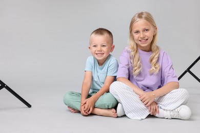 Photo of Little girl with her brother on light grey background in photo studio