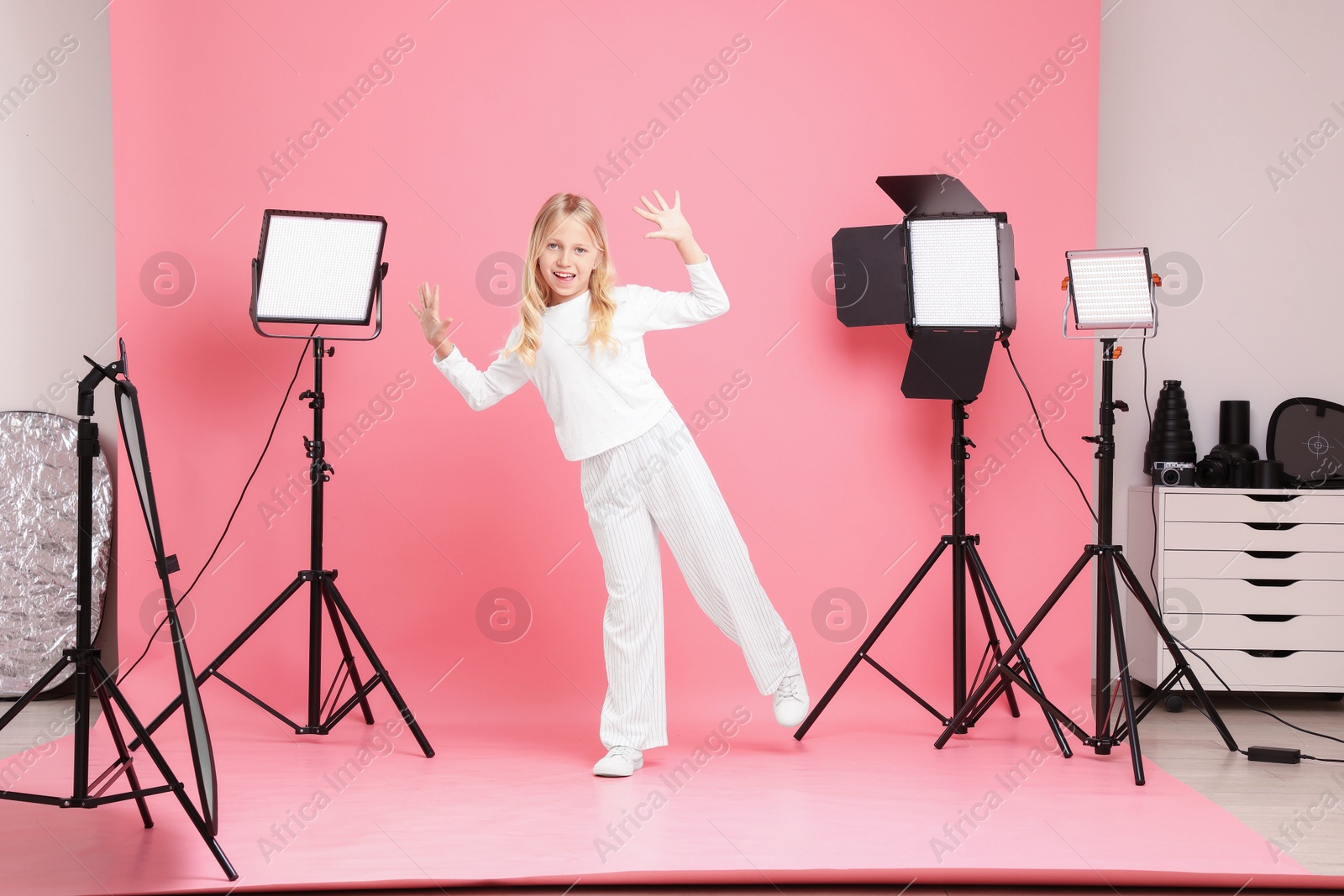 Photo of Little girl on pink background in photo studio with professional equipment