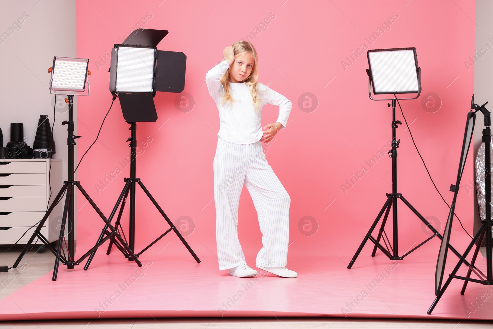 Little girl on pink background in photo studio with professional equipment Photo of Little girl on pink background in photo studio with professional equipment