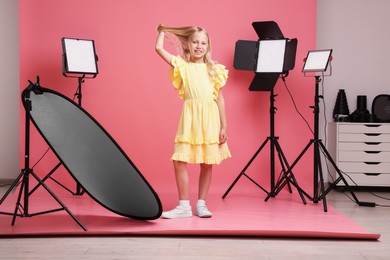 Photo of Little girl on pink background in photo studio with professional equipment