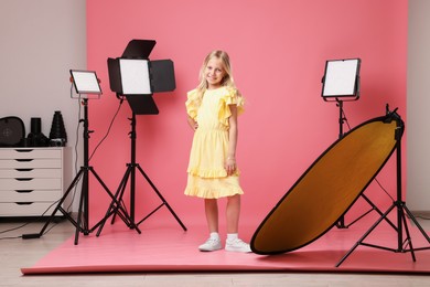 Photo of Little girl on pink background in photo studio with professional equipment
