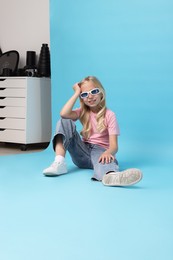 Photo of Little girl on light blue background in photo studio