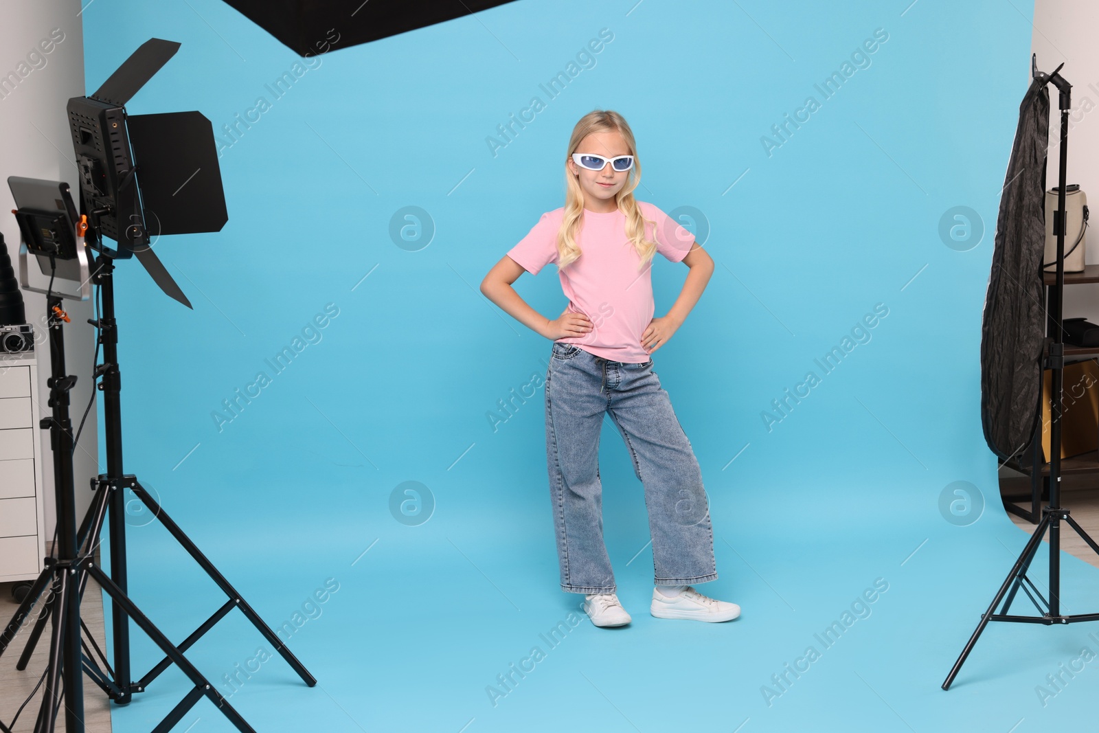 Little girl on light blue background in photo studio with professional equipment Photo of Little girl on light blue background in photo studio with professional equipment