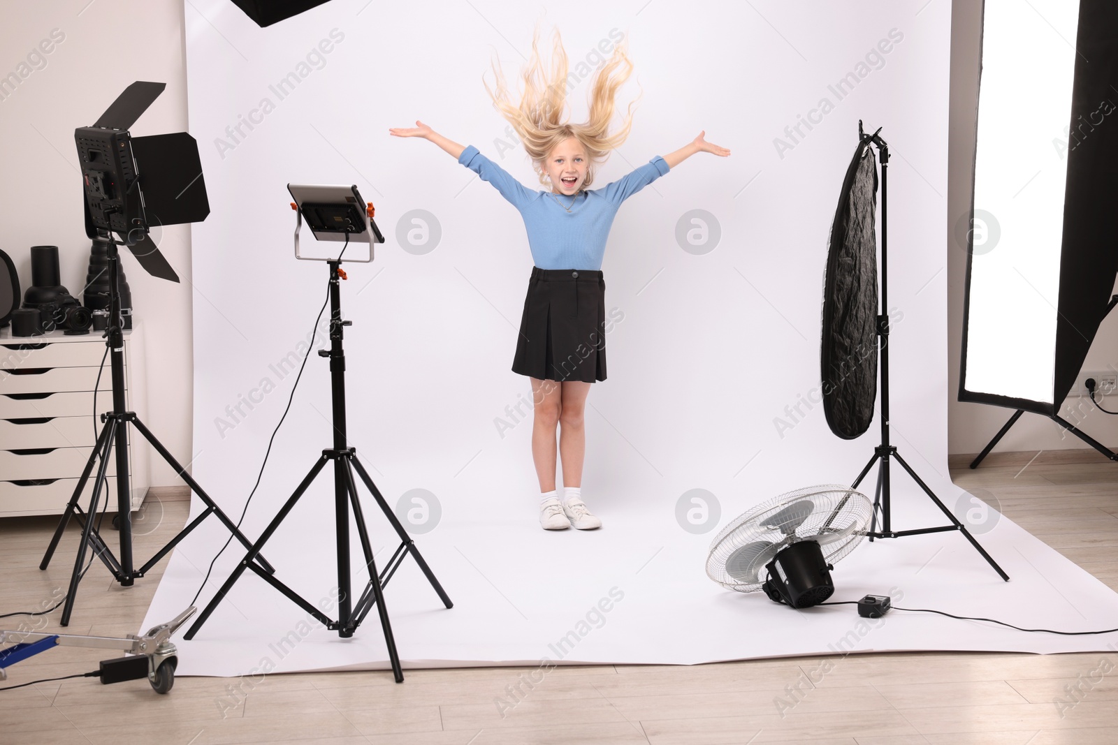 Little girl on white background in photo studio with professional equipment Photo of Little girl on white background in photo studio with professional equipment