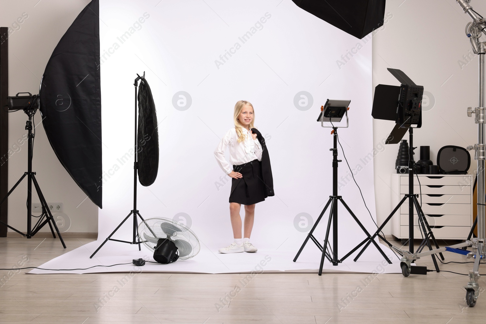 Little girl on white background in photo studio with professional equipment Photo of Little girl on white background in photo studio with professional equipment
