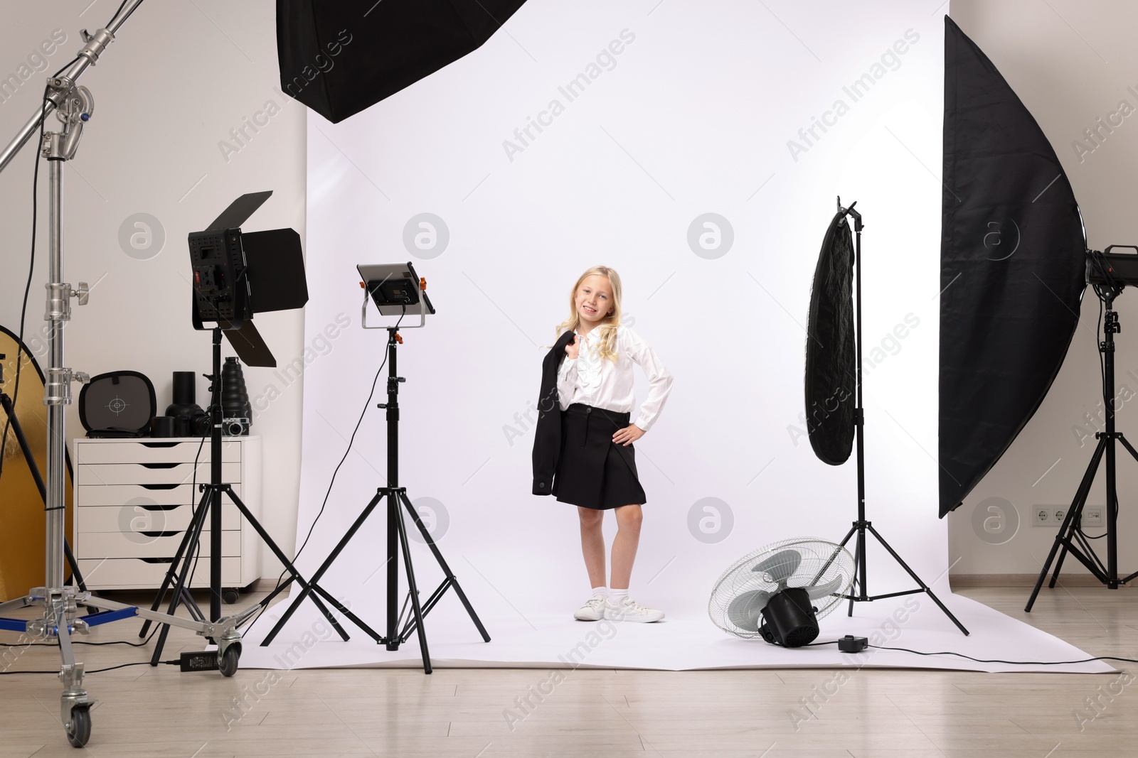 Little girl on white background in photo studio with professional equipment Photo of Little girl on white background in photo studio with professional equipment