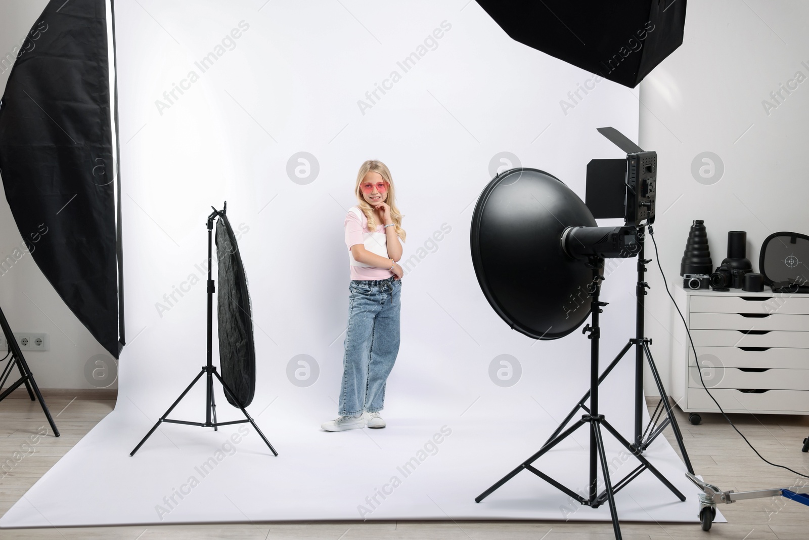 Little girl on white background in photo studio with professional equipment Photo of Little girl on white background in photo studio with professional equipment