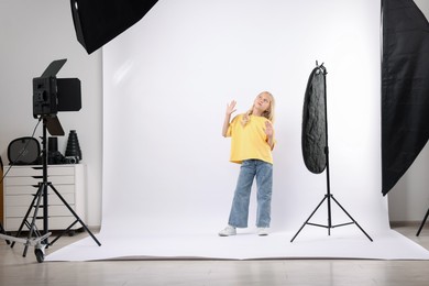 Photo of Little girl on white background in photo studio with professional equipment