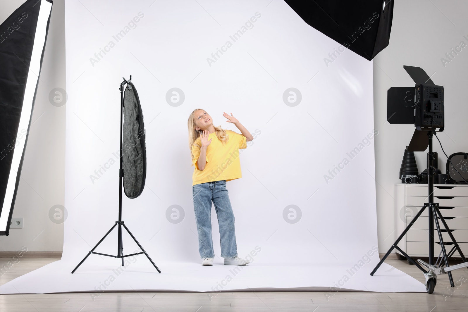 Little girl on white background in photo studio with professional equipment Photo of Little girl on white background in photo studio with professional equipment