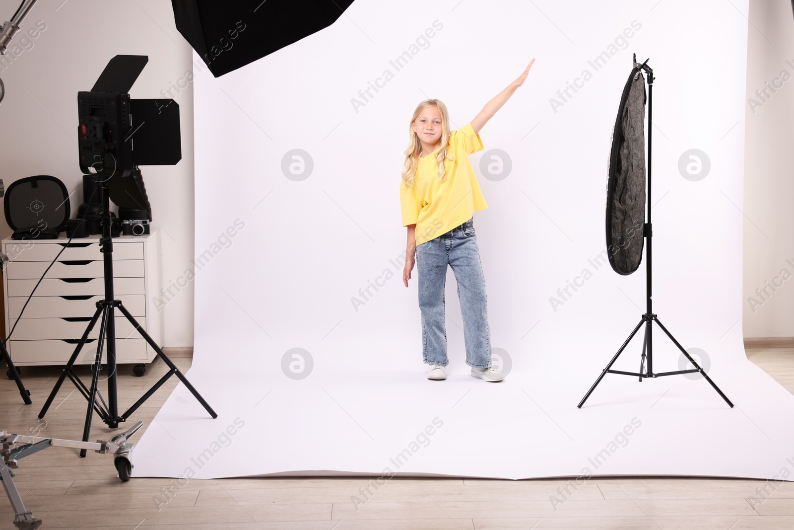 Little girl on white background in photo studio with professional equipment Photo of Little girl on white background in photo studio with professional equipment