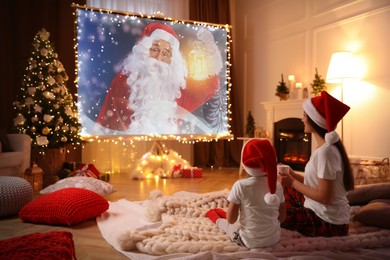 Image of Mother and daughter watching Christmas show using video projector at home