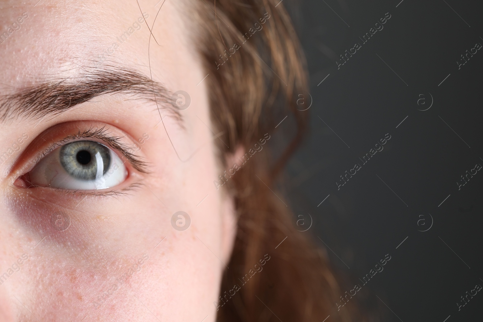 Photo of Woman with beautiful eyes on grey background, closeup. Space for text