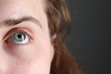 Photo of Woman with beautiful eyes on grey background, closeup. Space for text