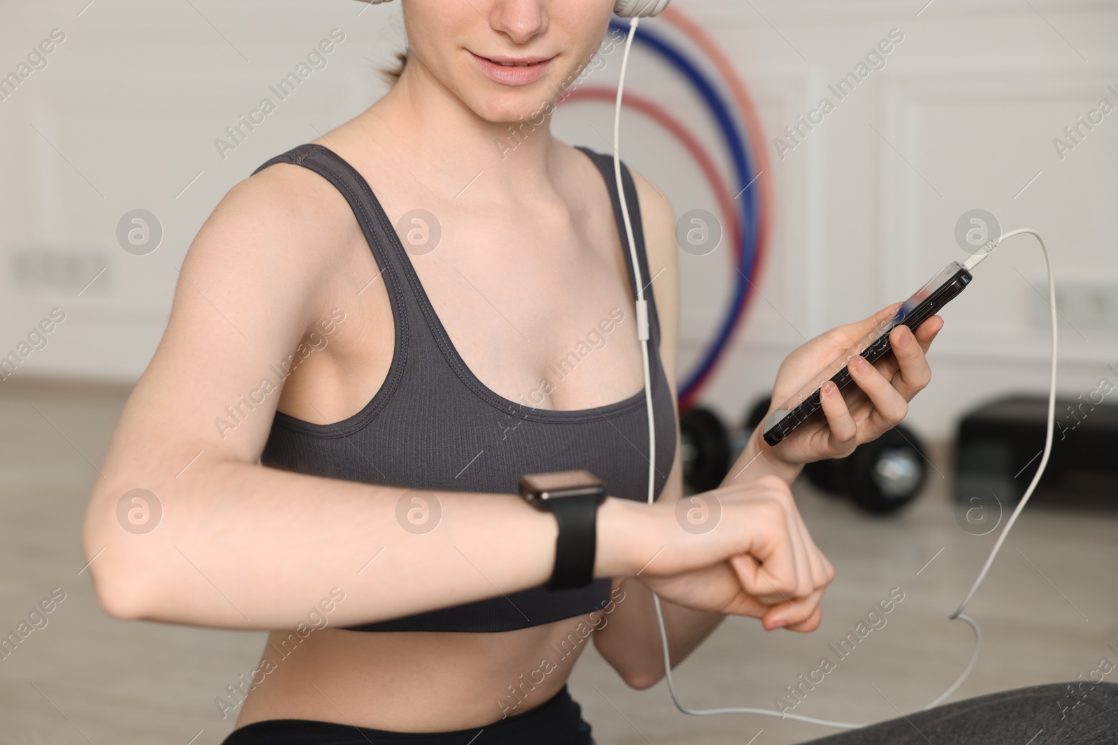 Woman checking fitness tracker during training indoors, closeup Photo of Woman checking fitness tracker during training indoors, closeup