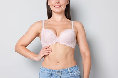 Photo of Woman wearing beautiful pink bra on light grey background, closeup