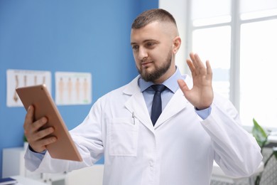 Photo of Doctor with tablet having online consultation in clinic
