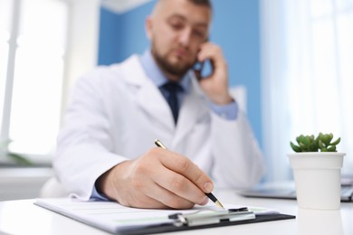 Photo of Doctor having online consultation via smartphone in clinic, selective focus