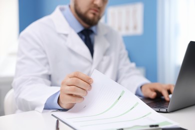 Photo of Doctor using laptop at table in clinic, selective focus. Online medical consultation