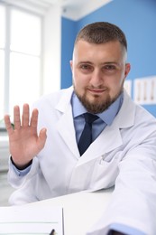 Photo of Doctor having online consultation at table in clinic