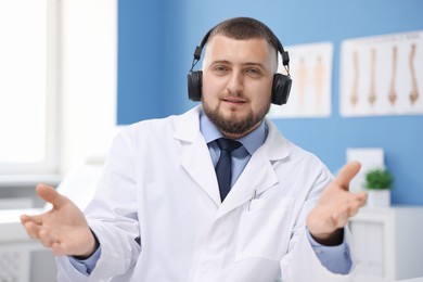 Photo of Doctor in headphones having online consultation indoors